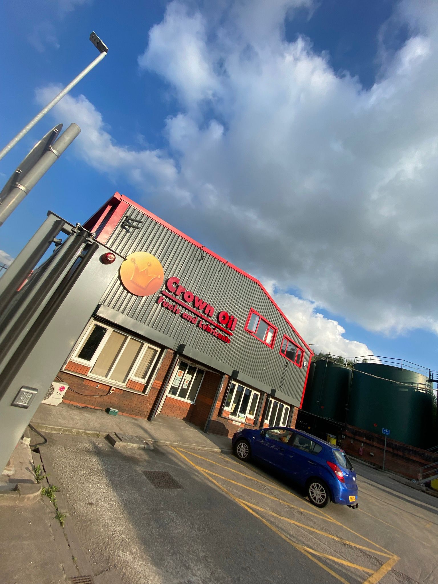 Industrial unit with freshly sprayed pink-red roof and grey cladding, sky behind