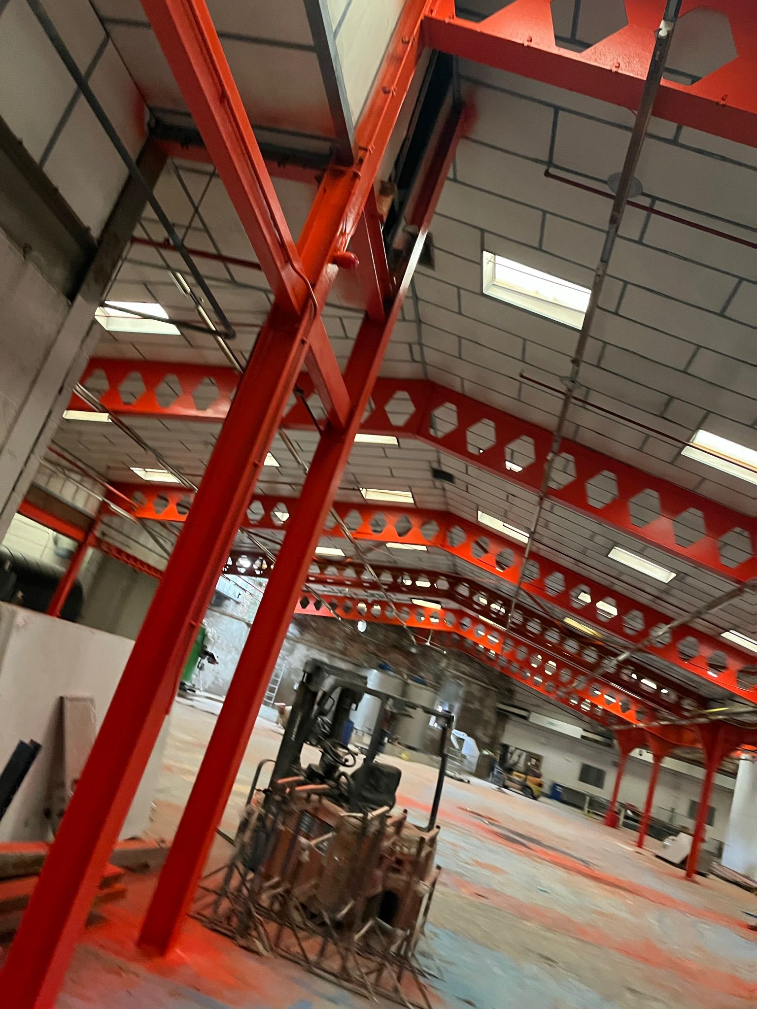 Red intumescent steelwork in warehouse, structural beams with circular cutouts